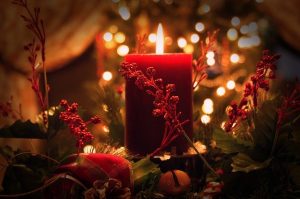 A lit red, column candle amid sparkly lights in a "candlelit" environment