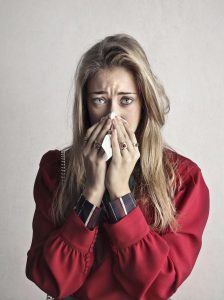 white woman with long blond hair, wearing a red blouse, crying into a tissue
